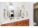 Bathroom with double sinks, wood cabinets, a large mirror, and modern lighting at 2100 Stone Pasture Rd, Fuquay Varina, NC 27526