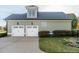 Attached two car garage with white doors, exterior lighting, and well manicured landscaping at 2100 Stone Pasture Rd, Fuquay Varina, NC 27526