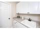 Bright laundry room with white cabinets, undermount sink and neutral countertops at 2100 Stone Pasture Rd, Fuquay Varina, NC 27526