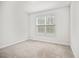 Neutral-toned bedroom features window with blinds and plush carpeting for a cozy and inviting atmosphere at 214 George Pine Way, Knightdale, NC 27545
