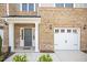 Close-up of a brick townhome featuring an attached garage, front door and manicured landscaping around the entrance at 214 George Pine Way, Knightdale, NC 27545
