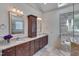Bathroom with dual sinks, dark wood cabinets, granite countertops, and a glass shower at 2312 Shallowford Ln, Chapel Hill, NC 27517