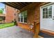 A covered outdoor patio with a brick wall, concrete floor, and a white door leading inside at 2740 Laurelcherry St, Raleigh, NC 27612