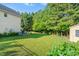 Spacious backyard featuring a lush lawn, mature trees, and a charming patio area with outdoor seating at 303 Sylvias Ct, Durham, NC 27703