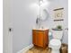 Half-bathroom with wood vanity, round mirror, toilet, and wall art with flooring at 303 Sylvias Ct, Durham, NC 27703