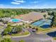 Aerial view showcasing community amenities: pool, clubhouse, beach volleyball, tennis and basketball courts, near a lake at 303 Sylvias Ct, Durham, NC 27703