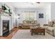 Bright living room featuring a fireplace, sofa, ottoman, ceiling fan, area rug, and view through the window at 303 Sylvias Ct, Durham, NC 27703