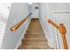 Carpeted staircase with wood railing leads to the upper level at 303 Sylvias Ct, Durham, NC 27703