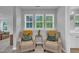 Inviting sitting area with two comfy chairs, decorative pillows, and natural light from the three windows at 325 Buckhorn Branch Park, Clayton, NC 27520