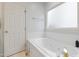 Bright bathroom featuring a soaking tub with white tile surround and frosted glass window at 327 Commons Walk Cir, Cary, NC 27519