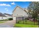 Side of the home with a two-car garage, green lawn and a black decorative fence at 327 Commons Walk Cir, Cary, NC 27519