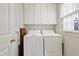 Bright laundry room with overhead cabinets and a window for natural light and ventilation at 327 Commons Walk Cir, Cary, NC 27519