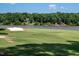 Scenic golf course view with sand trap, water, and tree-lined lake backdrop under a clear sky at 3285 Edinburgh Dr, Sanford, NC 27332