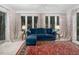 Sunlit living room with a plush blue sofa, decorative curtains, and a view of the outdoor greenery at 3285 Edinburgh Dr, Sanford, NC 27332