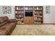 Cozy living room features custom wooden bookshelves and a comfortable brown leather couch with patterned rug at 3285 Edinburgh Dr, Sanford, NC 27332