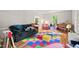 Inviting playroom featuring comfortable seating, a grand piano, and colorful play mats on hardwood floors at 3806 Lochnora Pkwy, Durham, NC 27705