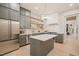 Well-lit kitchen with stainless steel appliances, gray cabinets, open shelving and central island at 4 Rainforest Pl, Apex, NC 27523
