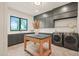 Well-equipped laundry room with sink, folding table, modern washer and dryer, and gray cabinets at 4 Rainforest Pl, Apex, NC 27523
