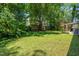 Backyard with green grass and view of the covered patio with furniture and grill at 4001 Pin Oak Rd, Raleigh, NC 27604