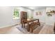 Sun-filled dining area with a modern wooden table set, adjacent to windows and a view of the updated kitchen at 4001 Pin Oak Rd, Raleigh, NC 27604