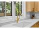 Bright kitchen sink with modern fixtures and a view to the lush outdoors through a large window at 411 Bon Air Ave, Durham, NC 27704
