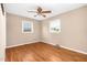 Warm bedroom featuring hardwood floors, two windows allowing natural light, and a ceiling fan for added comfort at 4536 Massey Rd, Zebulon, NC 27597
