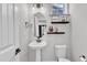 Well-lit bathroom with a pedestal sink, floating shelves, and modern fixtures providing a clean and stylish aesthetic at 520 Oak Holly Ln, Zebulon, NC 27597