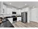 Modern kitchen featuring white cabinets, sleek black countertops, and stainless steel appliances for a chef's delight at 520 Oak Holly Ln, Zebulon, NC 27597