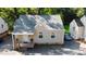 Aerial view of a quaint tan home with gray roof, showcasing the front porch, neat gravel landscaping, and surrounding greenery at 522 E Club Blvd, Durham, NC 27704