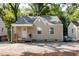 Charming, tan one-story home with gray roof, white trim and front porch surrounded by mature trees and gravel landscaping at 522 E Club Blvd, Durham, NC 27704