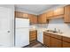 Compact kitchen featuring wood cabinetry, a double stainless steel sink, and a white refrigerator at 5911 Westcreek Pl, Raleigh, NC 27606