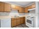 Efficient kitchen featuring ample wood cabinets, white appliances, and a stainless steel double sink at 5911 Westcreek Pl, Raleigh, NC 27606