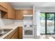 Well-lit kitchen with wood cabinets, modern white appliances, and a sliding glass door to the outdoor deck at 5911 Westcreek Pl, Raleigh, NC 27606