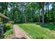 Spacious backyard featuring lush green grass, mature trees, and a brick pathway leading to the house at 608 Misty Isle Pl, Raleigh, NC 27615