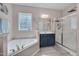 Well-lit bathroom featuring a soaking tub, shower, and vanity with navy cabinets at 62 Mountain Laurel Ln, Four Oaks, NC 27524