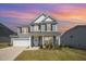 Charming two-story home with a well-manicured lawn, attached garage, and inviting front porch against a vibrant sky at 645 Longstanton Ave, Zebulon, NC 27597