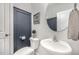 Modern half bathroom with blue accent wall, white sink, and a stylish round mirror at 645 Longstanton Ave, Zebulon, NC 27597