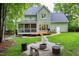 Charming backyard showcasing a spacious deck, a stone pathway and fire pit, all surrounded by lush greenery at 709 Bonhurst Dr, Holly Springs, NC 27540