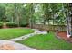 Expansive backyard featuring lush green grass, mature trees, and a charming stone fire pit area for outdoor enjoyment at 709 Bonhurst Dr, Holly Springs, NC 27540