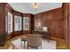 Traditional office with rich wood paneling, built-in shelves and bright natural light from multiple windows at 104 Bellagio Dr, Apex, NC 27539