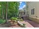 View of backyard with stone retaining wall, patio, steps to screened in porch, and wooded views at 104 Bellagio Dr, Apex, NC 27539