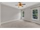 Neutral bedroom with two windows, ceiling fan, plush carpet and decorative crown moulding at 104 Bellagio Dr, Apex, NC 27539