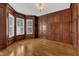 A den with hardwood floors, paneled walls, bay windows, and a decorative light fixture at 104 Bellagio Dr, Apex, NC 27539