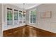 Bright dining room featuring hardwood floors, wainscoting, large windows, and a stylish light fixture at 104 Bellagio Dr, Apex, NC 27539