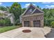 Detached two-car garage featuring stone facade, carriage doors, and well-manicured landscaping at 104 Bellagio Dr, Apex, NC 27539