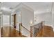 A second story hallway with hardwood floors, decorative railing, chandelier and crown molding at 104 Bellagio Dr, Apex, NC 27539