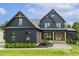Stunning modern farmhouse with dark siding, gabled roofs, and manicured lawn at 1141 Duke Farm Dr, Wake Forest, NC 27587