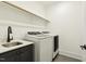 Functional laundry room with modern washer and dryer units, and utility sink at 1141 Duke Farm Dr, Wake Forest, NC 27587
