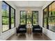 Bright sunroom with black framed windows, cozy chairs, and wooded backyard view at 1141 Duke Farm Dr, Wake Forest, NC 27587