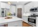 Kitchen view showcasing stainless steel appliances, white countertops and cabinets, and hardwood floors at 118 Fox Run Ct, Durham, NC 27705